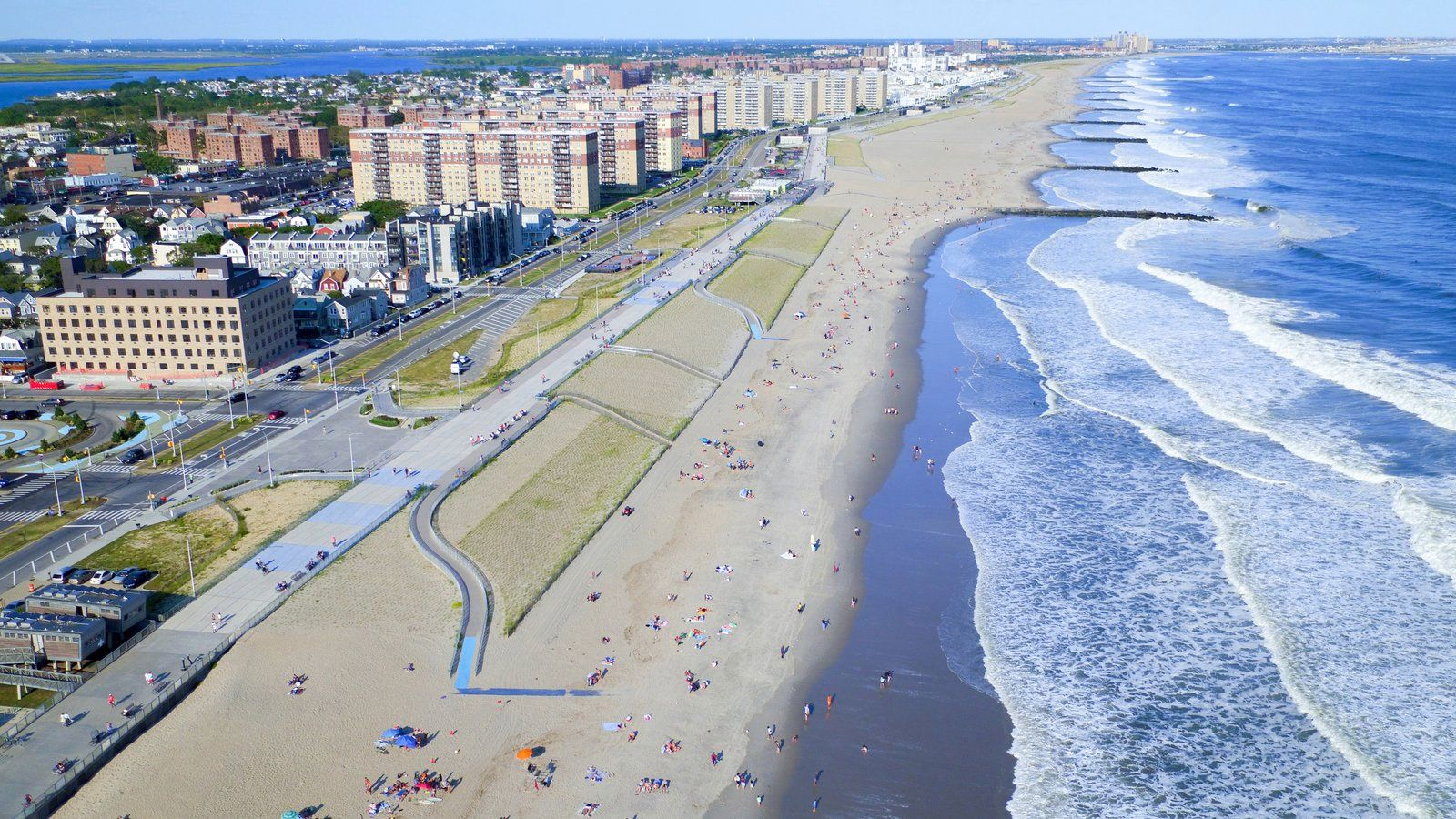 Rockaway Beach with surfers and beachgoers on a sunny day